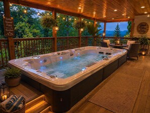 Ein Whirlpool mit Holzterrasse, umgeben von Topfpflanzen und einem Schild mit der Aufschrift 'Good Vibes Only'.