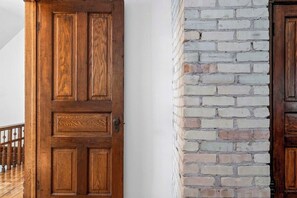 A wooden door with a metal handle and a brick wall. - The Blue Victorian | Near Downtown Traverse City (Traverse City)