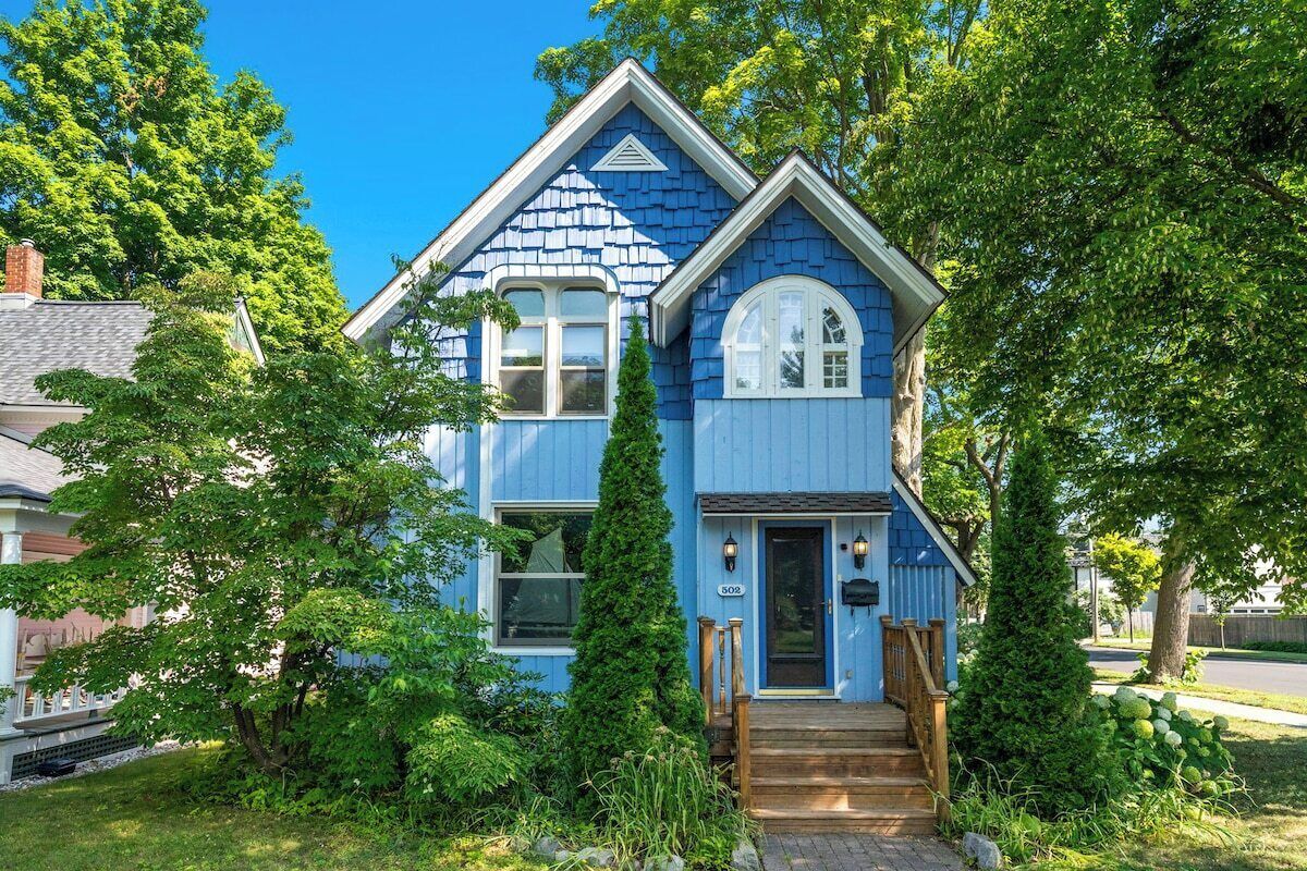 A two-story house with a blue exterior, a front porch, and a mailbox.