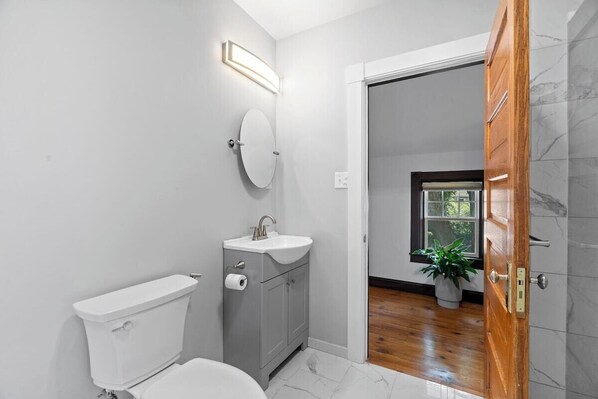 Uma casa de banho moderna com sanita, lavatório e espelho.