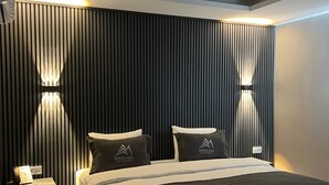 A modern hotel room with a large bed, two bedside tables, and a wall-mounted light fixture.