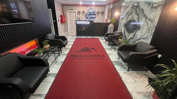A reception area with a red carpet, black leather chairs, a reception desk, and a marble wall.