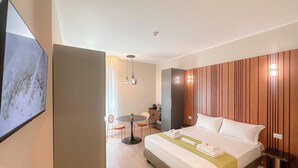 A hotel room with a bed, bedside table, and a small dining area with chairs. - Flatsharing Design Studio - Moka (Milan)