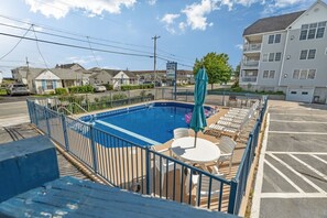 Ein Swimmingpool mit Liegestühlen und einem Tisch, umgeben von einem Zaun.