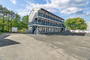 A two-story building with a balcony on the upper floor, a parking lot in front, and trees in the background. - Beachside Escape-Old Orchard Beach (Old Orchard Beach)