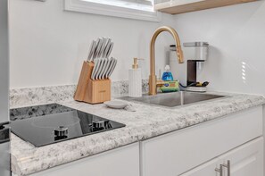 A kitchen with a marble countertop, a built-in stove, a sink with a gold faucet, and a knife block. - Beachside Escape-Old Orchard Beach (Old Orchard Beach)