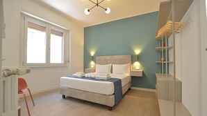 Ein modernes Schlafzimmer mit Bett, Nachttischen, einem Kleiderschrank und einem Fenster.