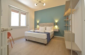 Ein modernes Schlafzimmer mit Bett, Nachttischen, einem Kleiderschrank und einem Fenster.