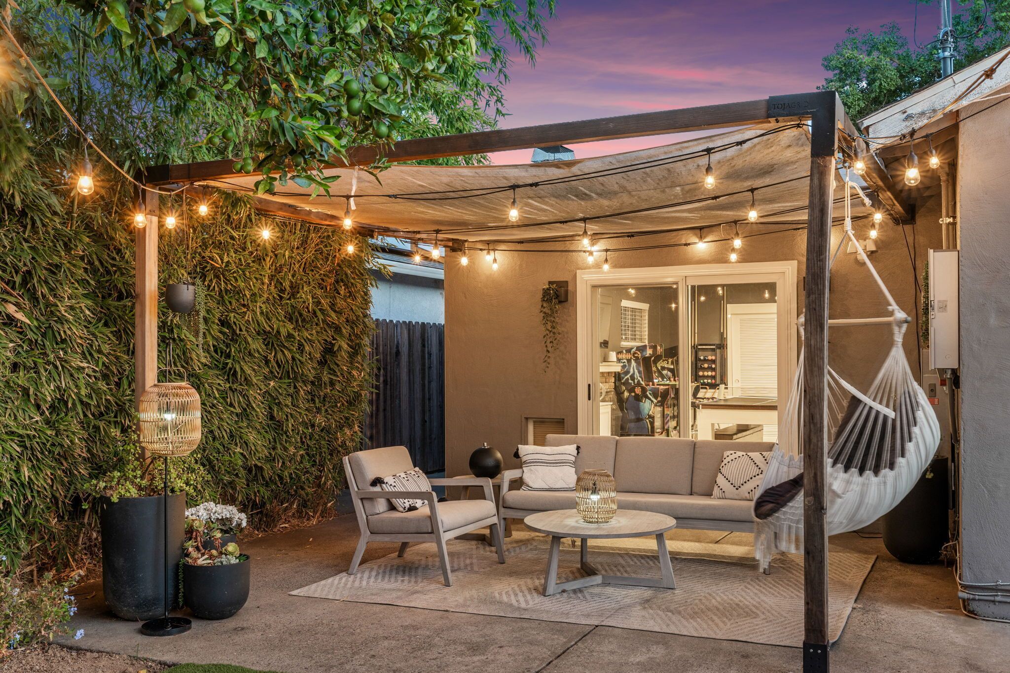 An outdoor patio with a seating area, string lights, and a hanging hammock.