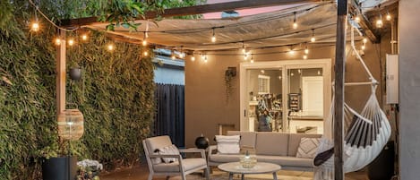 An outdoor patio with a seating area, string lights, and a hanging hammock.