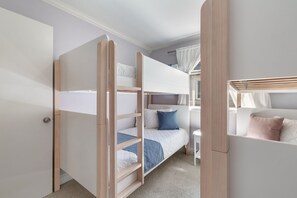 Una habitación con literas, un escritorio y una ventana con cortinas.