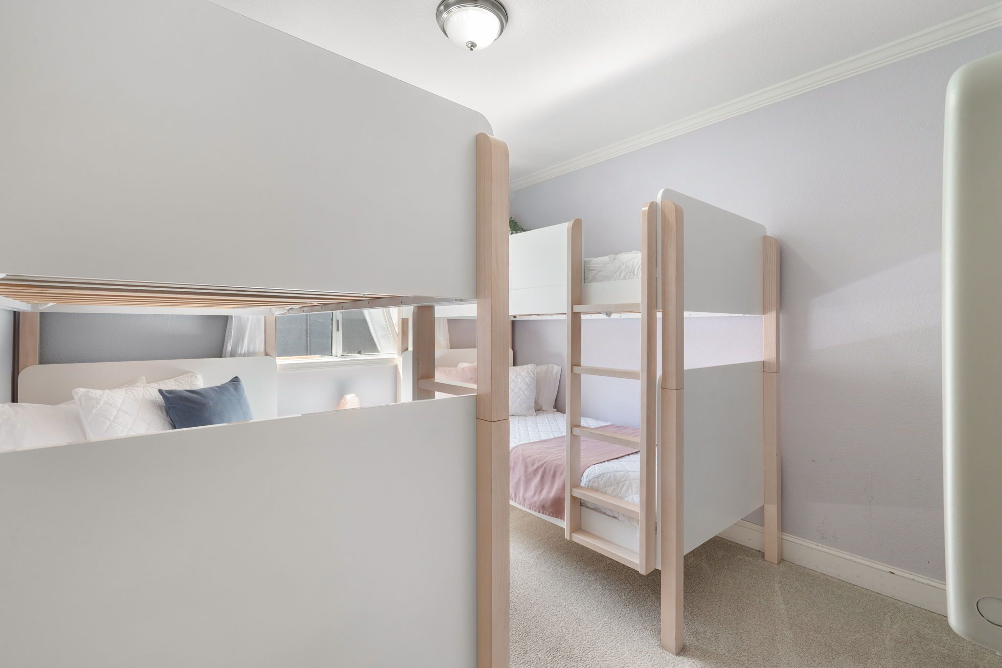 A room with bunk beds, a window, and a door.