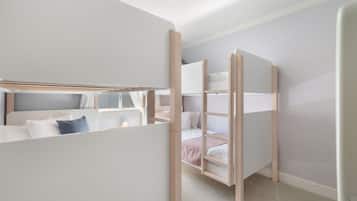 A room with bunk beds, a window, and a door.