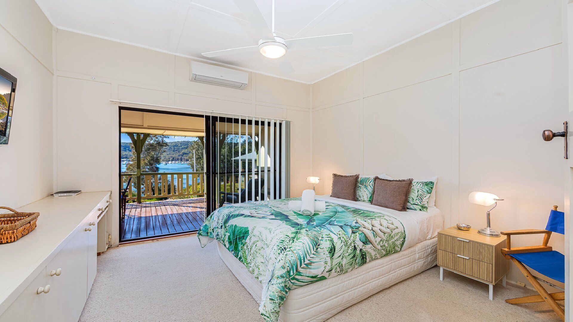 A bedroom with a bed, bedside table, lamp, and a view of the outdoors through a sliding door.