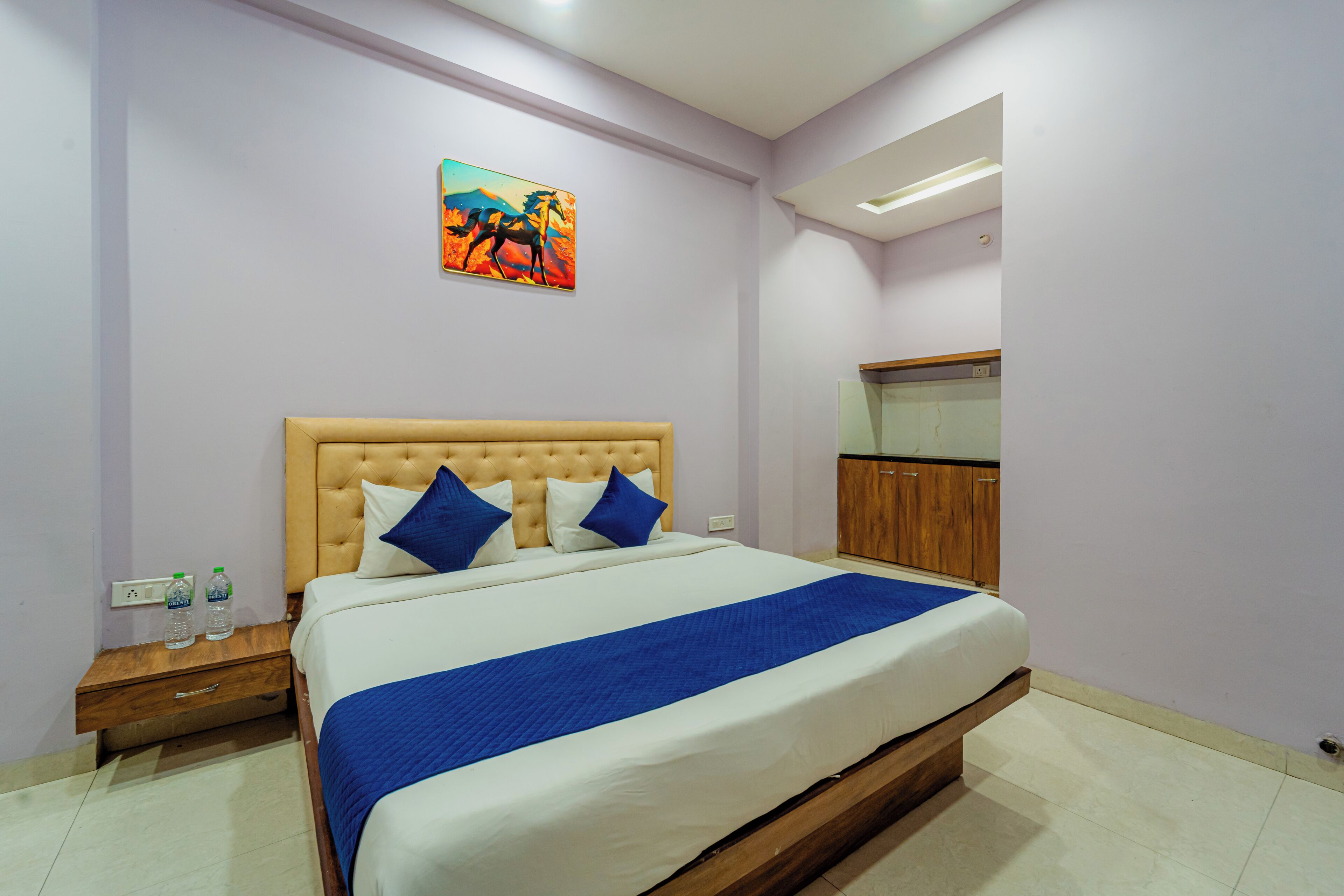 A bedroom with a bed, a nightstand, a wardrobe, and a painting on the wall.