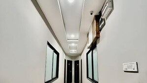 Un pasillo con una lámpara en el techo, un detector de humo y un interruptor de luz en la pared.