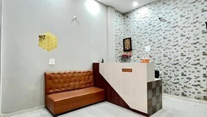 Un área de recepción con un sofá, mostrador de recepción, ventilador de techo y azulejos de pared estampados.