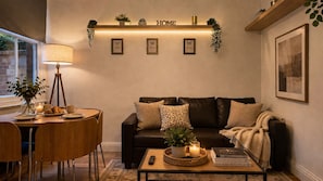 Un salon chaleureux avec un canapé en cuir foncé, une table basse ronde en bois et une étagère murale agrémentée d’objets décoratifs.