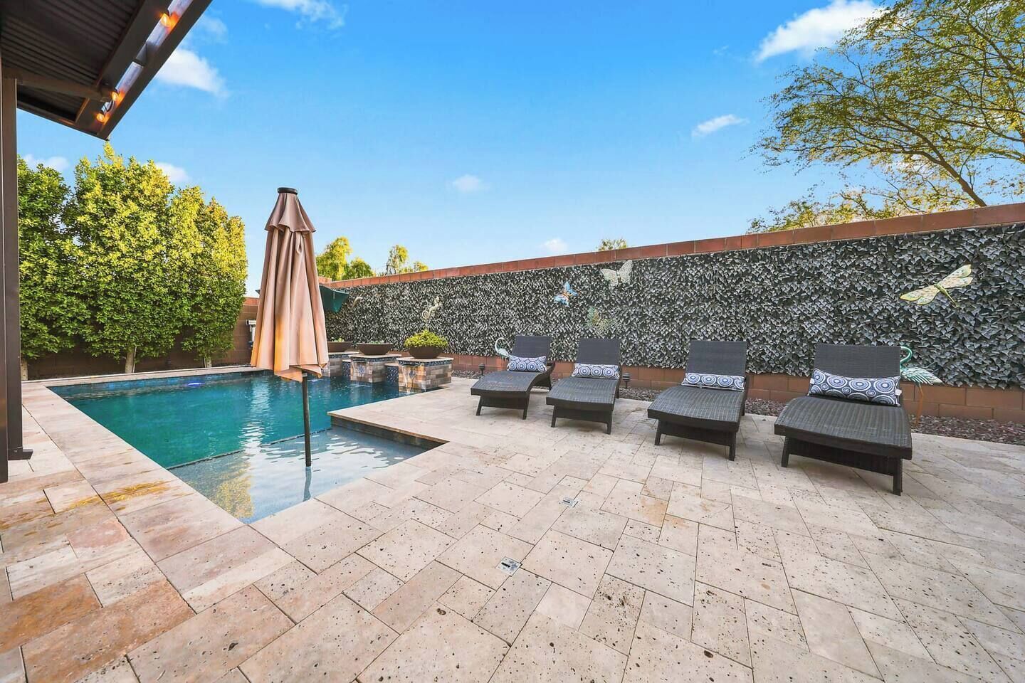 A poolside area with lounge chairs and a decorative wall.