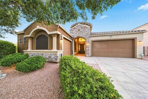 A two-story house with a stone facade, a garage, and a well-maintained driveway. - Modern 5BR Pool Home Sleeps 15 Walk to Stadium (Glendale)