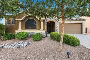 A residential house with a stone facade, a large arched window, and a garage. - Modern 5BR Pool Home Sleeps 15 Walk to Stadium (Glendale)