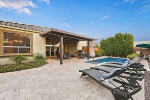 A residential backyard with a swimming pool, outdoor seating, and a covered patio area. - Modern 5BR Pool Home Sleeps 15 Walk to Stadium (Glendale)