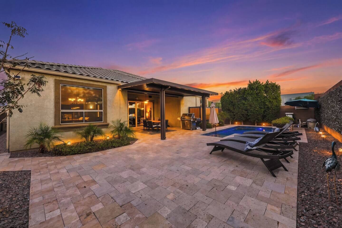 A residential property with a swimming pool, patio area, and a covered outdoor seating space.