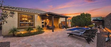 A residential property with a swimming pool, patio area, and a covered outdoor seating space.