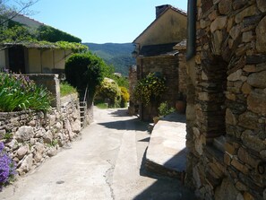 A narrow stone pathway leading through a rustic village with traditional stone buildings and lush greenery. - Delphine's House (saint martin de l'arçon)