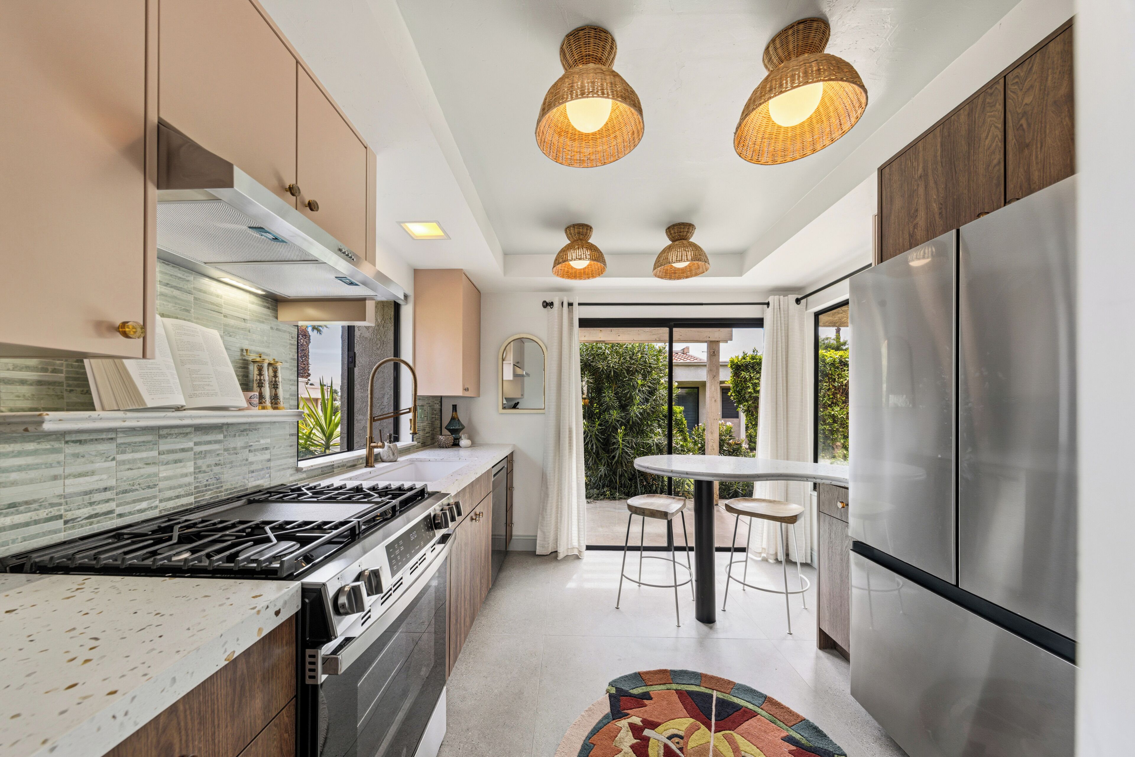 A modern kitchen with a stainless steel refrigerator, a gas stove, and a dining area with a table and chairs.