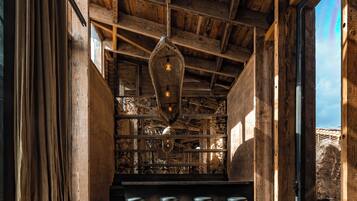 Un interior rústico con vigas de madera a la vista, una lámpara colgante y una zona de bar con taburetes.