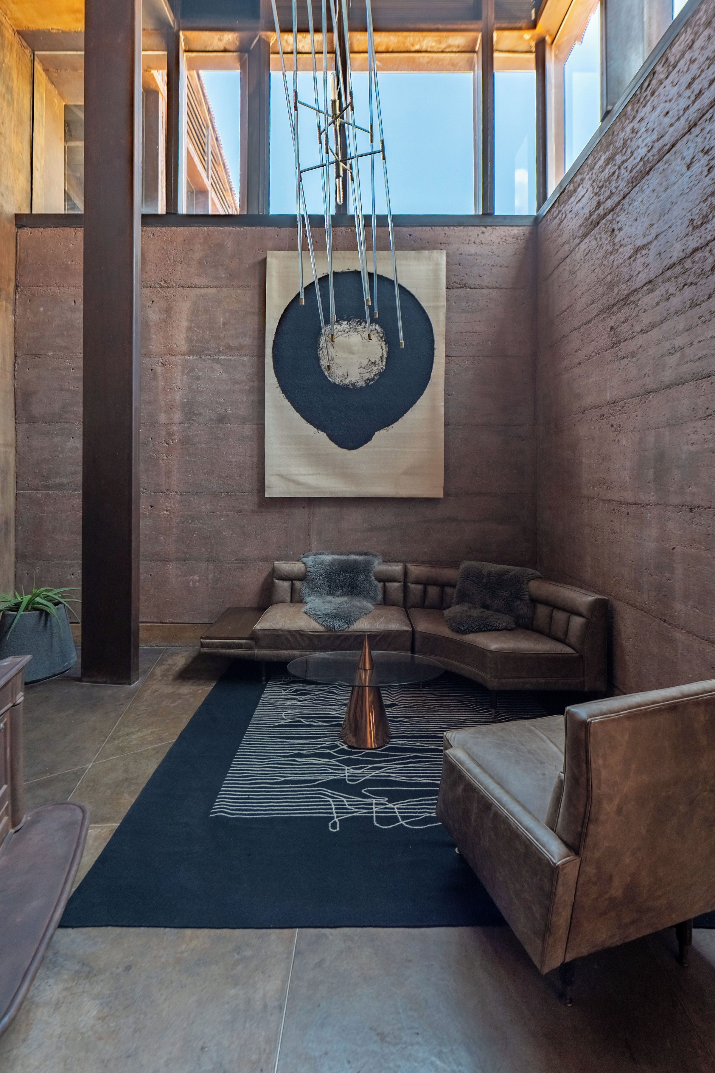 A modern interior with a sectional sofa, a coffee table, and a large abstract painting on the wall.