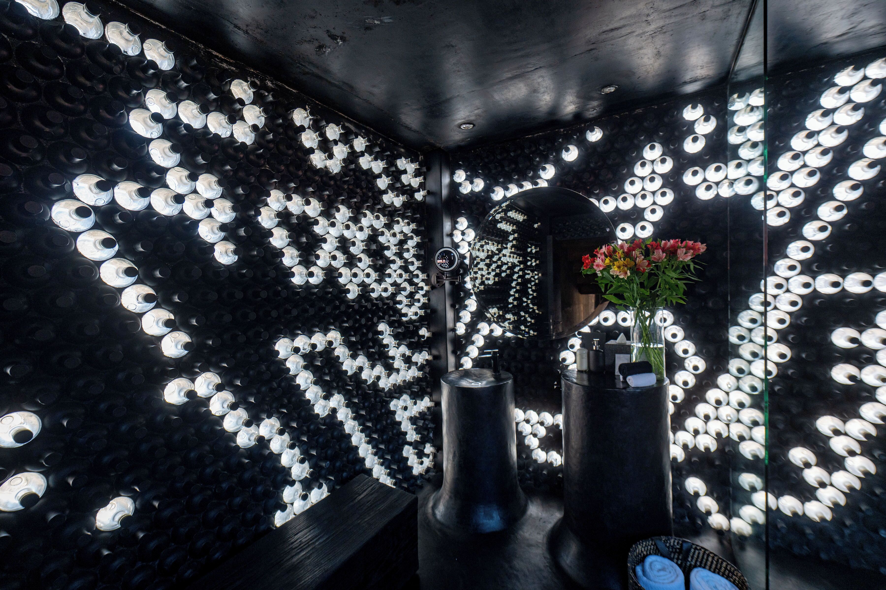 A room with a patterned wall, a mirror, and a vase with flowers.