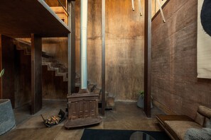 Una habitación con chimenea, una escalera y un ventanal grande.