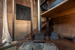 Una habitación con paredes de madera, una chimenea, una escalera y una gran pizarra en la pared.