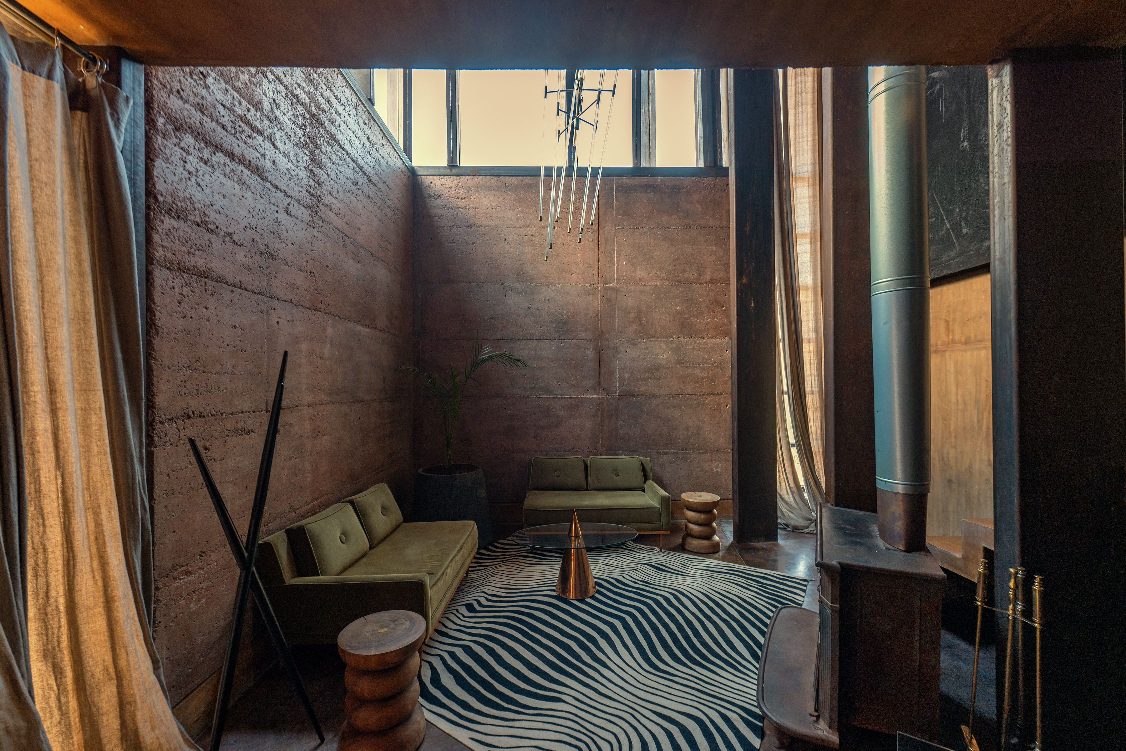 A room with a green sofa, a zebra-patterned rug, and a large window.