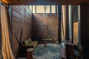A room with a green sofa, a zebra-patterned rug, and a large window.