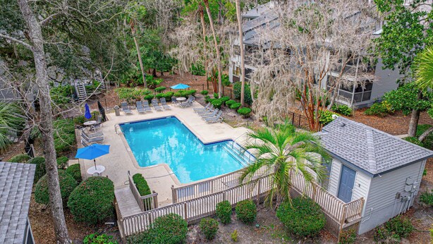 A swimming pool surrounded by lounge chairs and umbrellas, with a wooden deck and a small building nearby. - 3BR Ocean Breeze Escape | Walk to Beach at Coligny (Hilton Head Island)