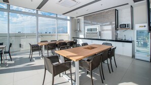 Eine moderne Küche mit großem Fenster, einem Essbereich mit Holztisch und -stühlen sowie einer Mikrowelle.