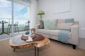 A modern living room with a sofa, a coffee table, and a view of the city through large windows. - Corporate Stays First Living - 907 (Asunción)