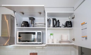 A kitchen with a built-in microwave, a kettle, a blender, and a coffee maker. - Corporate Stays First Living - 907 (Asunción)