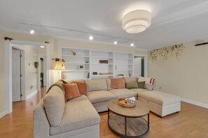 A modern living room with a sectional sofa, a round coffee table, and built-in shelving. - Private Blue Ridge 3BR Haven, Luxury Hot Tub (Bakersville)