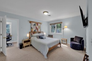 A bedroom with a bed, bedside tables, a chair, a lamp, and a TV mounted on the wall. - Private Blue Ridge 3BR Haven, Luxury Hot Tub (Bakersville)