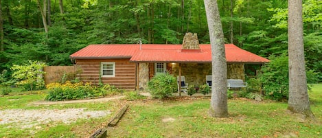 A cabin with a red roof, surrounded by a forest.
