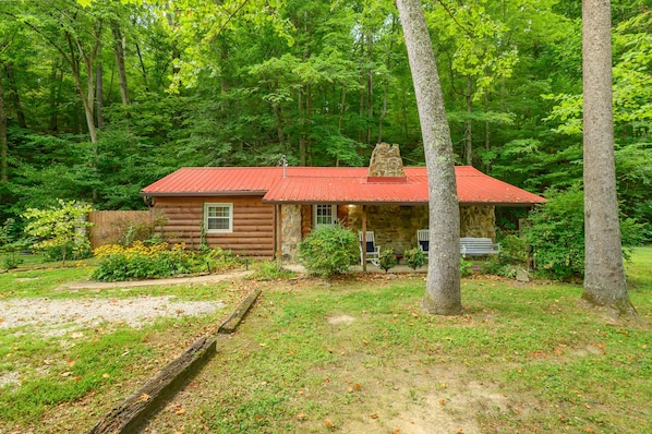 A cabin with a red roof, surrounded by a forest.