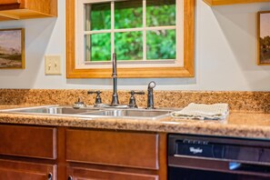 A kitchen with a granite countertop, stainless steel sink, and wooden cabinets. - A Peaceful Brown County Getaway Close to the State Park (Nashville)
