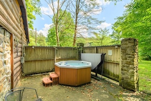A backyard with a wooden hot tub, stone walls, and a wooden fence.