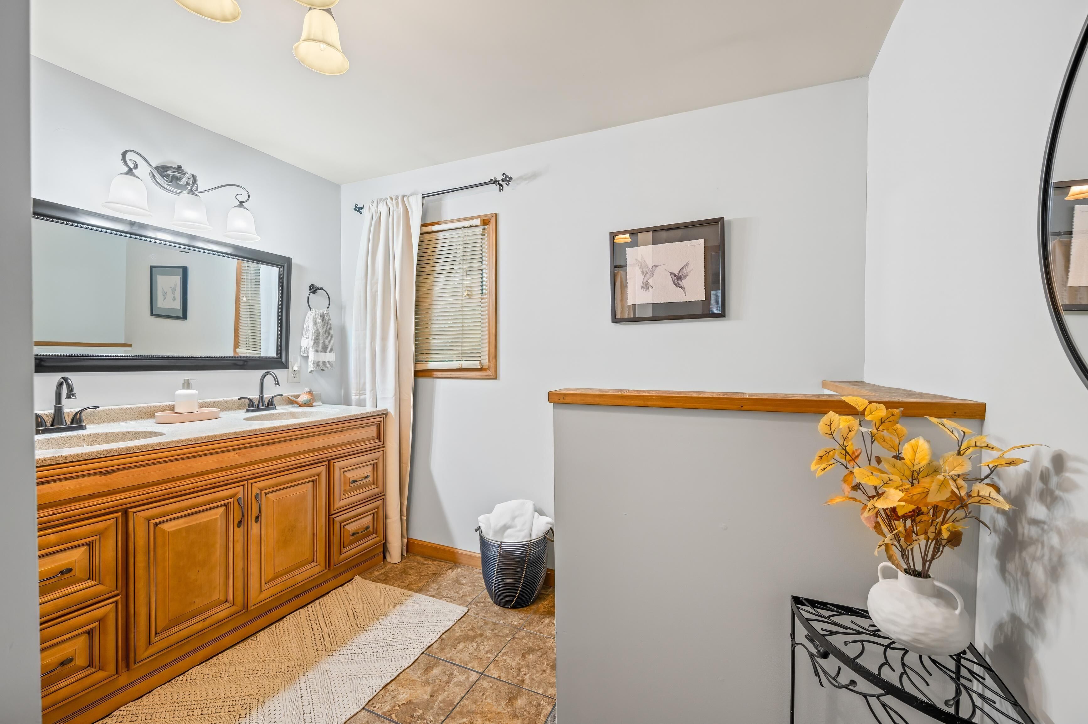 A bathroom with a wooden vanity, a large mirror, a towel rack, and a framed picture on the wall.