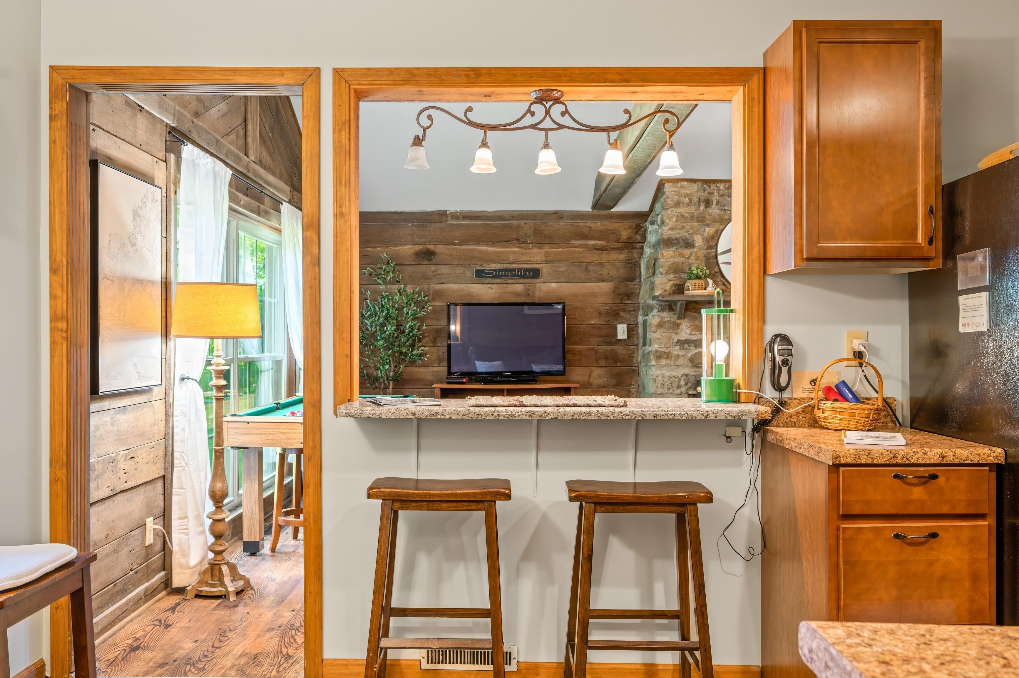 A kitchen with wooden cabinets, a built-in TV, and a stone accent wall.