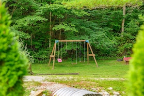 A wooden swing set in a grassy area surrounded by dense green foliage. - A Peaceful Brown County Getaway Close to the State Park (Nashville)
